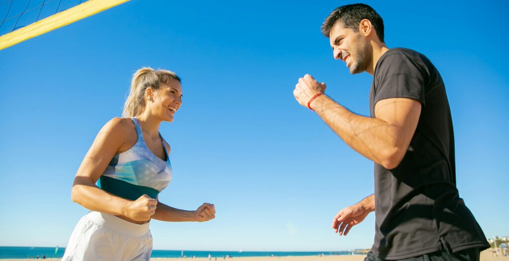 Two joyful players celebrate during a beach volleyball game on a sunny day, showcasing teamwork and fun.