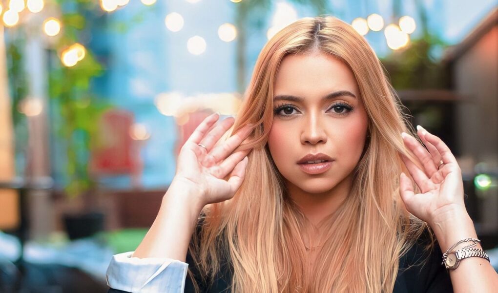 Young woman with blonde hair posing stylishly outdoors, capturing a modern fashion essence.
