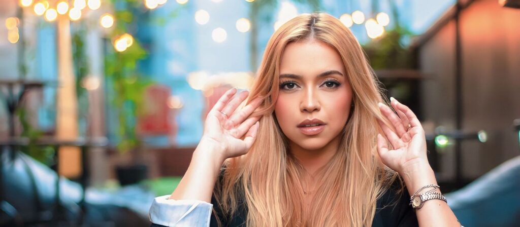 Young woman with blonde hair posing stylishly outdoors, capturing a modern fashion essence.