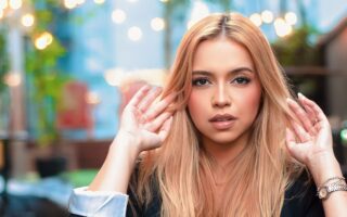 Young woman with blonde hair posing stylishly outdoors, capturing a modern fashion essence.