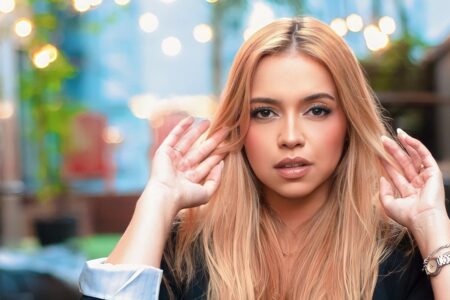 Young woman with blonde hair posing stylishly outdoors, capturing a modern fashion essence.